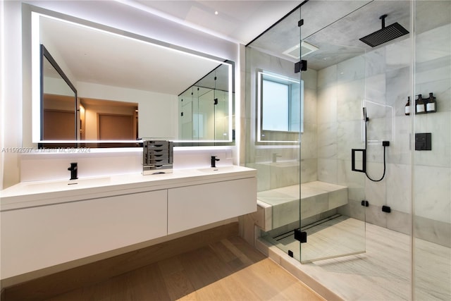 bathroom with large vanity, an enclosed shower, hardwood / wood-style floors, and dual sinks