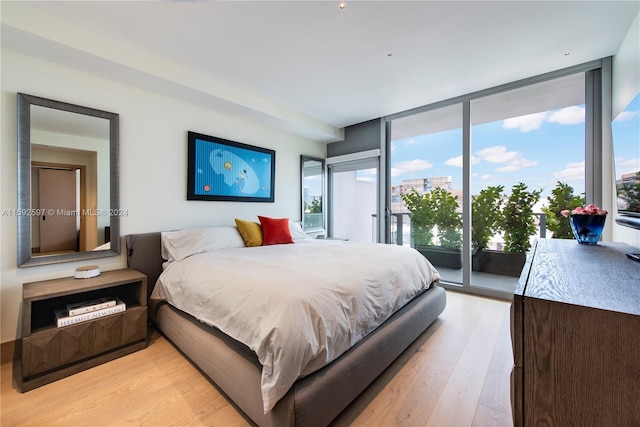 bedroom featuring expansive windows, light hardwood / wood-style floors, and access to exterior