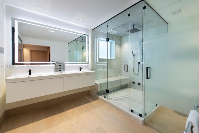 bathroom with dual bowl vanity, hardwood / wood-style floors, and a shower with door