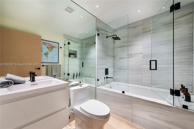 bathroom featuring tile flooring, bath / shower combo with glass door, and toilet