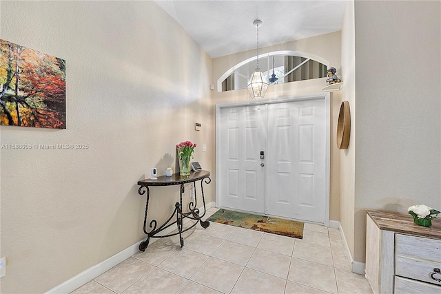 foyer entrance with baseboards, light tile patterned flooring, and a notable chandelier