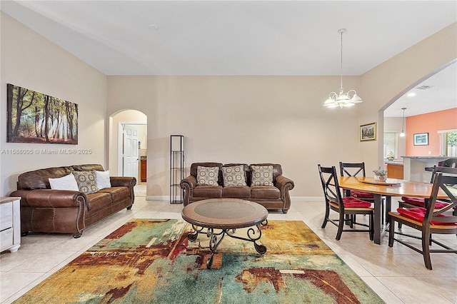 living room with light tile patterned floors, baseboards, visible vents, arched walkways, and an inviting chandelier