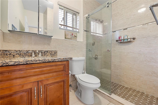 bathroom with toilet, a stall shower, vanity, and tile walls