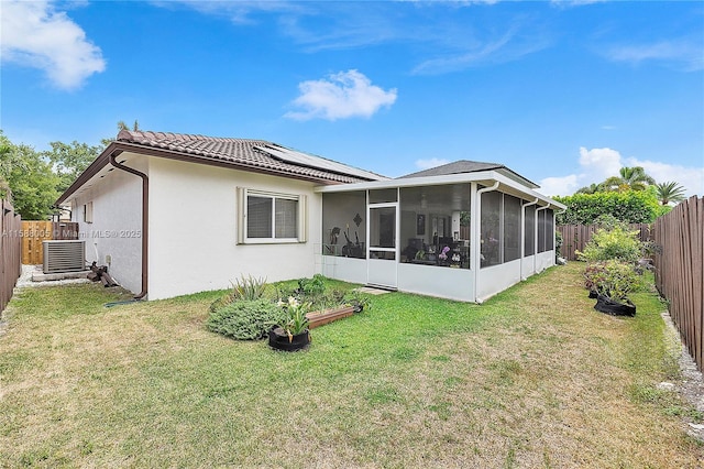 rear view of house with central AC, a yard, a fenced backyard, and a sunroom