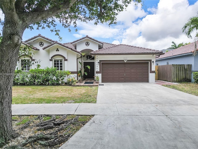 mediterranean / spanish home featuring a garage, fence, driveway, stucco siding, and a front lawn