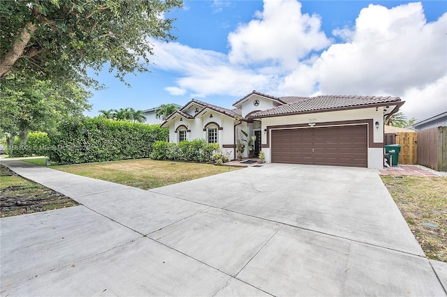 mediterranean / spanish-style home featuring driveway, a garage, a tiled roof, a front lawn, and stucco siding