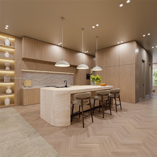 kitchen with a kitchen island with sink, light countertops, light brown cabinetry, modern cabinets, and decorative light fixtures