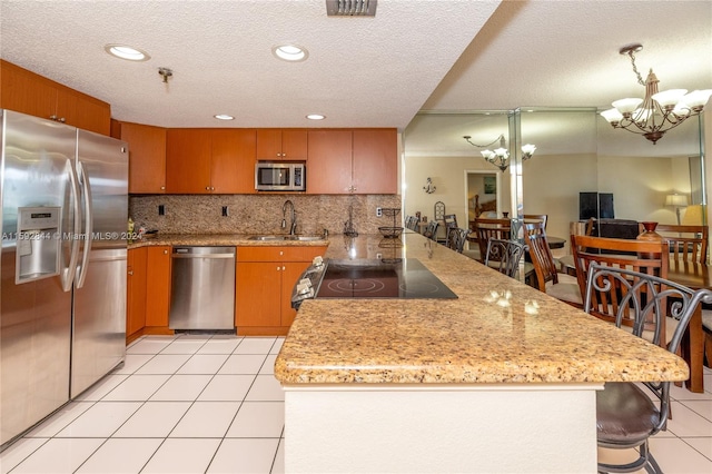 kitchen featuring backsplash, an inviting chandelier, appliances with stainless steel finishes, and sink