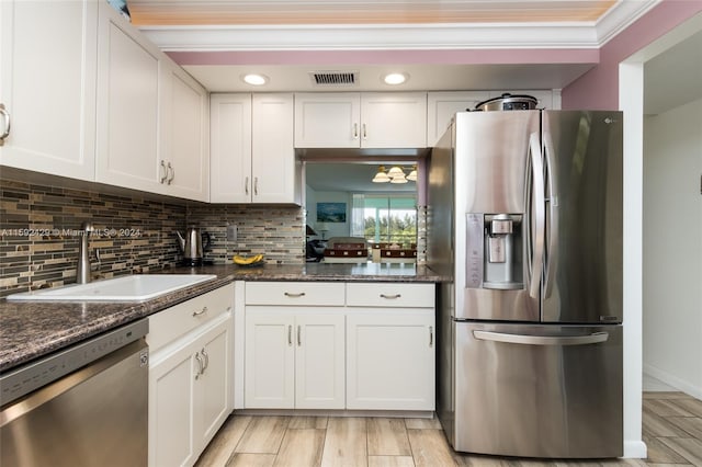 kitchen with dark stone counters, backsplash, sink, white cabinetry, and appliances with stainless steel finishes