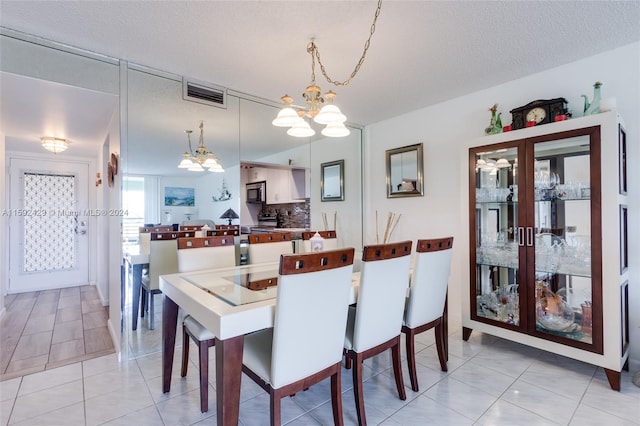 dining room with a notable chandelier, a textured ceiling, and light tile floors