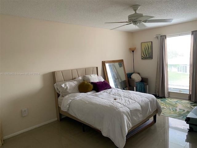 bedroom featuring tile flooring, ceiling fan, and a textured ceiling