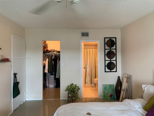 bedroom featuring a spacious closet, tile flooring, connected bathroom, and a textured ceiling