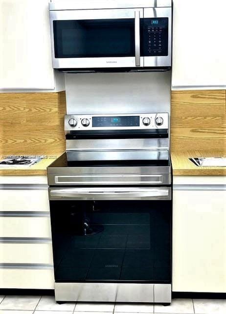 kitchen featuring white cabinets, stainless steel appliances, and light tile patterned flooring