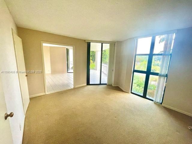 spare room with light carpet, a textured ceiling, and baseboards