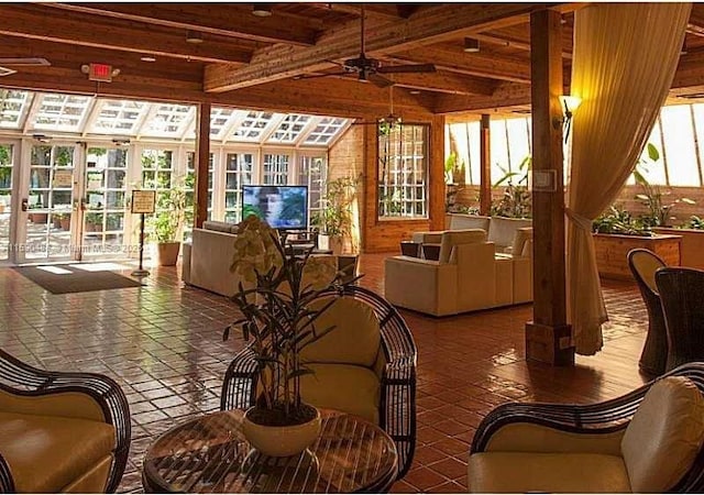 sunroom featuring beam ceiling, ceiling fan, and french doors