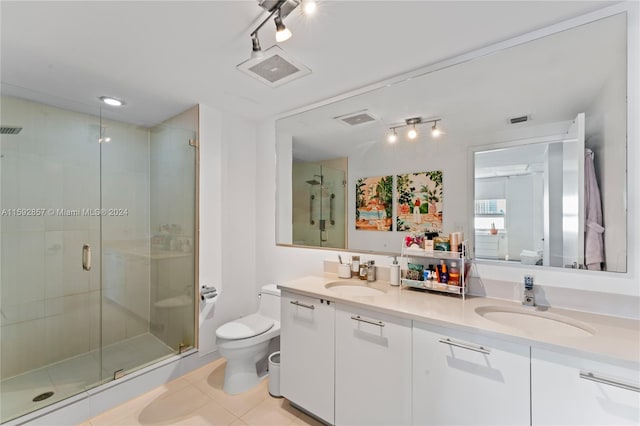 bathroom featuring tile flooring, dual vanity, walk in shower, rail lighting, and toilet