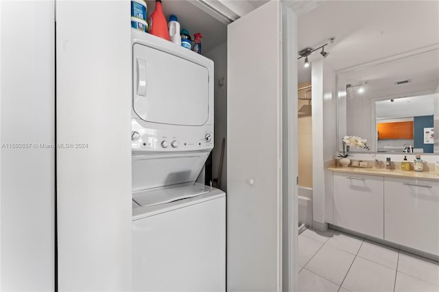 washroom with stacked washer / dryer and light tile floors