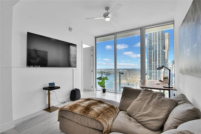 living room with light hardwood / wood-style floors, a wall of windows, a water view, and ceiling fan