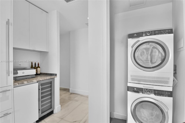 laundry area featuring light wood-type flooring, wine cooler, and stacked washing maching and dryer