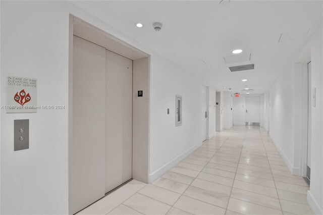 hall featuring light tile patterned flooring and elevator