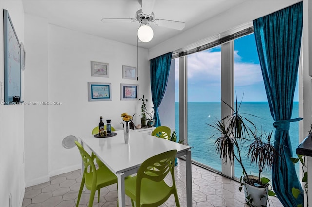 dining space featuring tile patterned floors, ceiling fan, and a water view