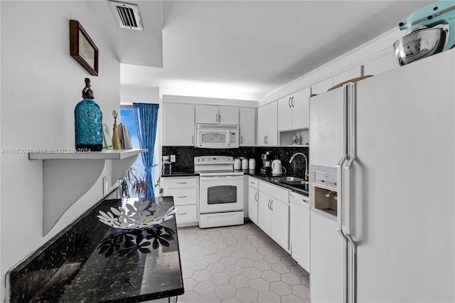 kitchen with white appliances, white cabinets, dark tile patterned flooring, sink, and tasteful backsplash