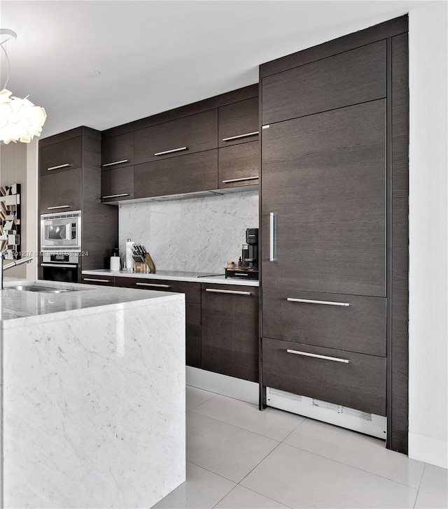 kitchen with light stone counters, appliances with stainless steel finishes, backsplash, and light tile floors