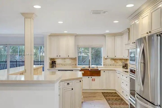 kitchen with sink, tasteful backsplash, stainless steel refrigerator, and light wood-type flooring