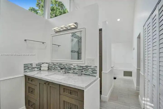 bathroom with tile flooring, vanity, and tasteful backsplash