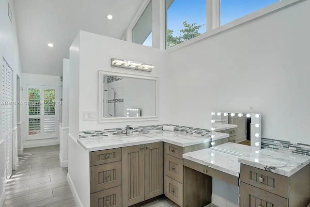 bathroom with high vaulted ceiling, backsplash, vanity, and tile floors