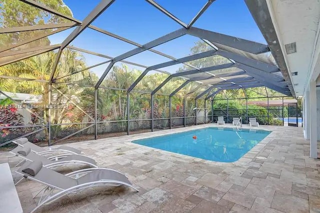 view of swimming pool with a patio area and a lanai