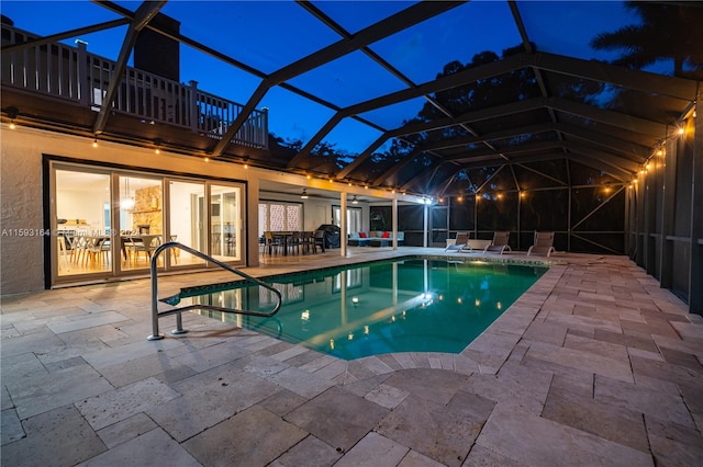 pool at twilight featuring a lanai and a patio