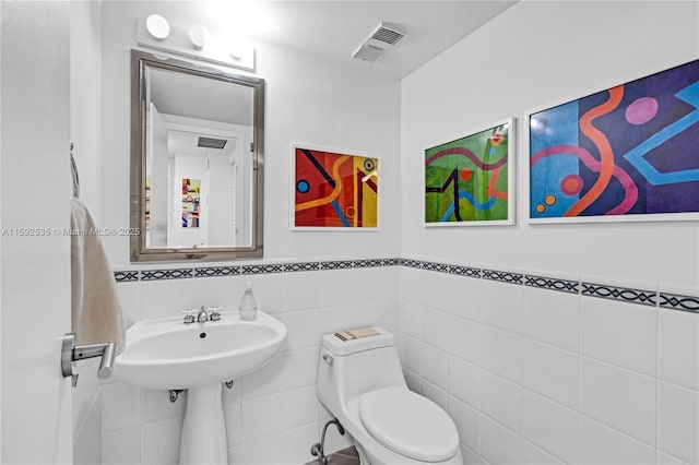 bathroom with toilet and tile walls