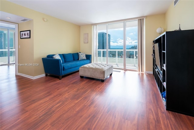 living room featuring wood-type flooring and a wall of windows