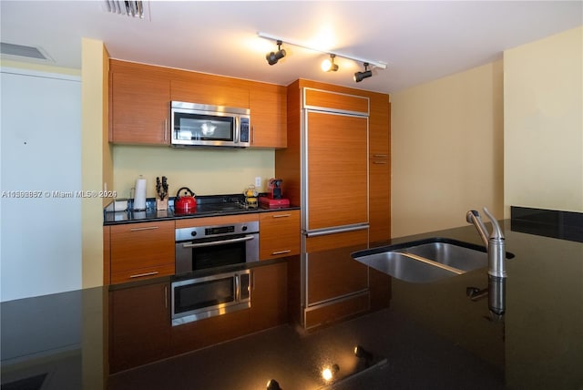 kitchen featuring sink, track lighting, and appliances with stainless steel finishes