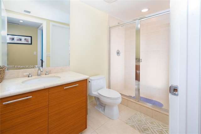 bathroom with an enclosed shower, tile flooring, vanity, and toilet