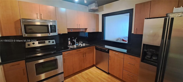 kitchen featuring sink, backsplash, stainless steel appliances, track lighting, and light hardwood / wood-style flooring