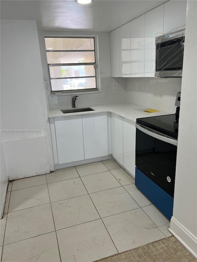 kitchen featuring light tile flooring, backsplash, white cabinetry, electric range oven, and sink