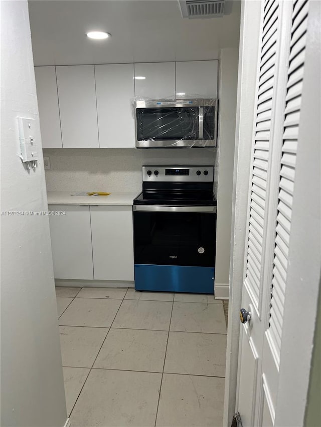 kitchen with white cabinets, light tile flooring, and appliances with stainless steel finishes