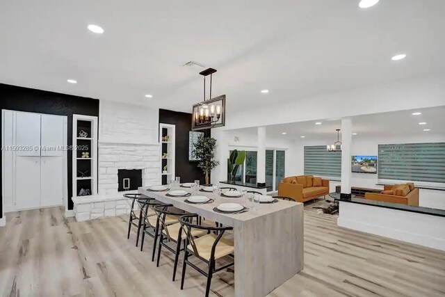 kitchen with a stone fireplace, pendant lighting, a notable chandelier, and light wood-type flooring