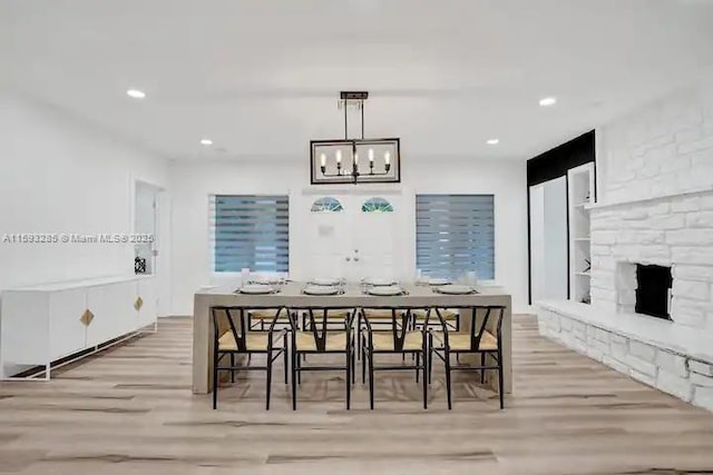 kitchen featuring a chandelier, a fireplace, light wood-type flooring, and decorative light fixtures