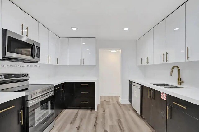 kitchen featuring sink, white cabinets, a kitchen bar, light hardwood / wood-style floors, and stainless steel refrigerator with ice dispenser