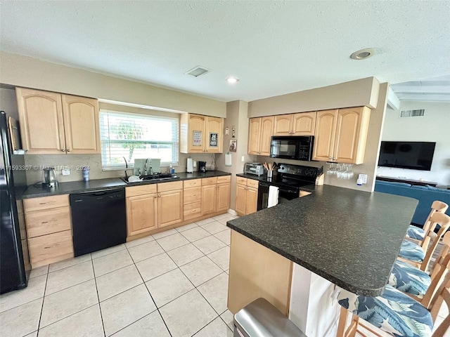 kitchen with black appliances, sink, light tile floors, and light brown cabinets