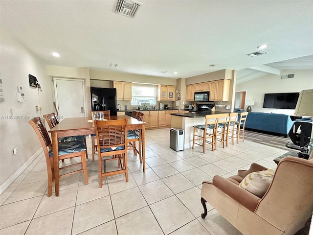 dining room featuring sink, vaulted ceiling, and light tile flooring