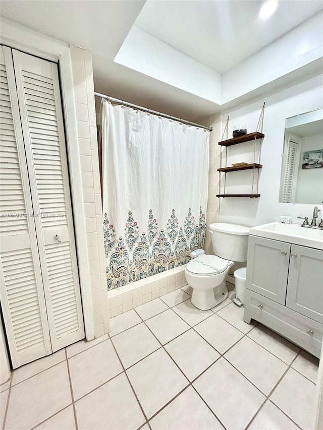 bathroom with tile floors, a tray ceiling, toilet, and vanity