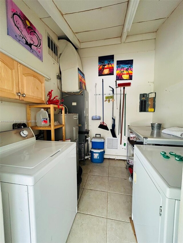 clothes washing area featuring cabinets, separate washer and dryer, and light tile floors