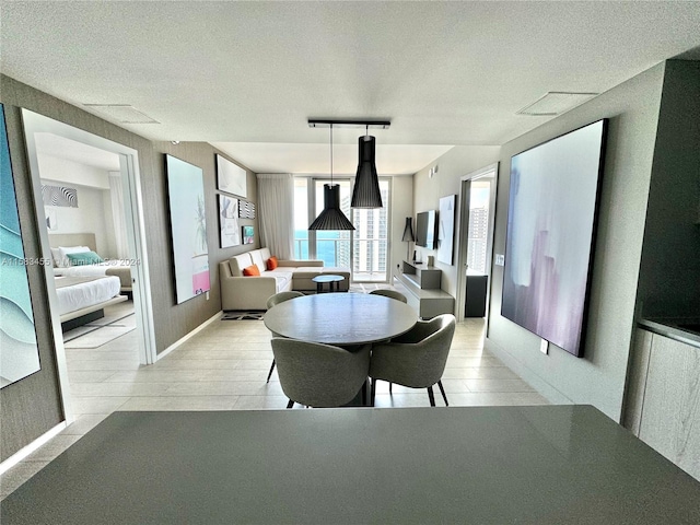 dining area with rail lighting, light hardwood / wood-style flooring, and a textured ceiling