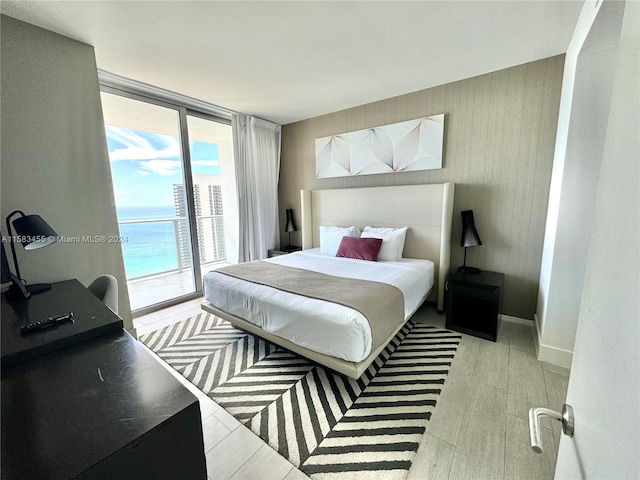 bedroom featuring light hardwood / wood-style flooring, access to exterior, and a wall of windows