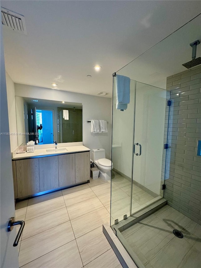 bathroom featuring tile patterned flooring, toilet, an enclosed shower, and vanity