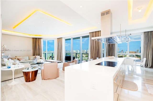 kitchen featuring a chandelier, a kitchen island, island exhaust hood, a tray ceiling, and black electric cooktop